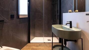 Een moderne badkamer met een vrijstaand bad, een wastafelmeubel met een wastafel en een douchehoek.