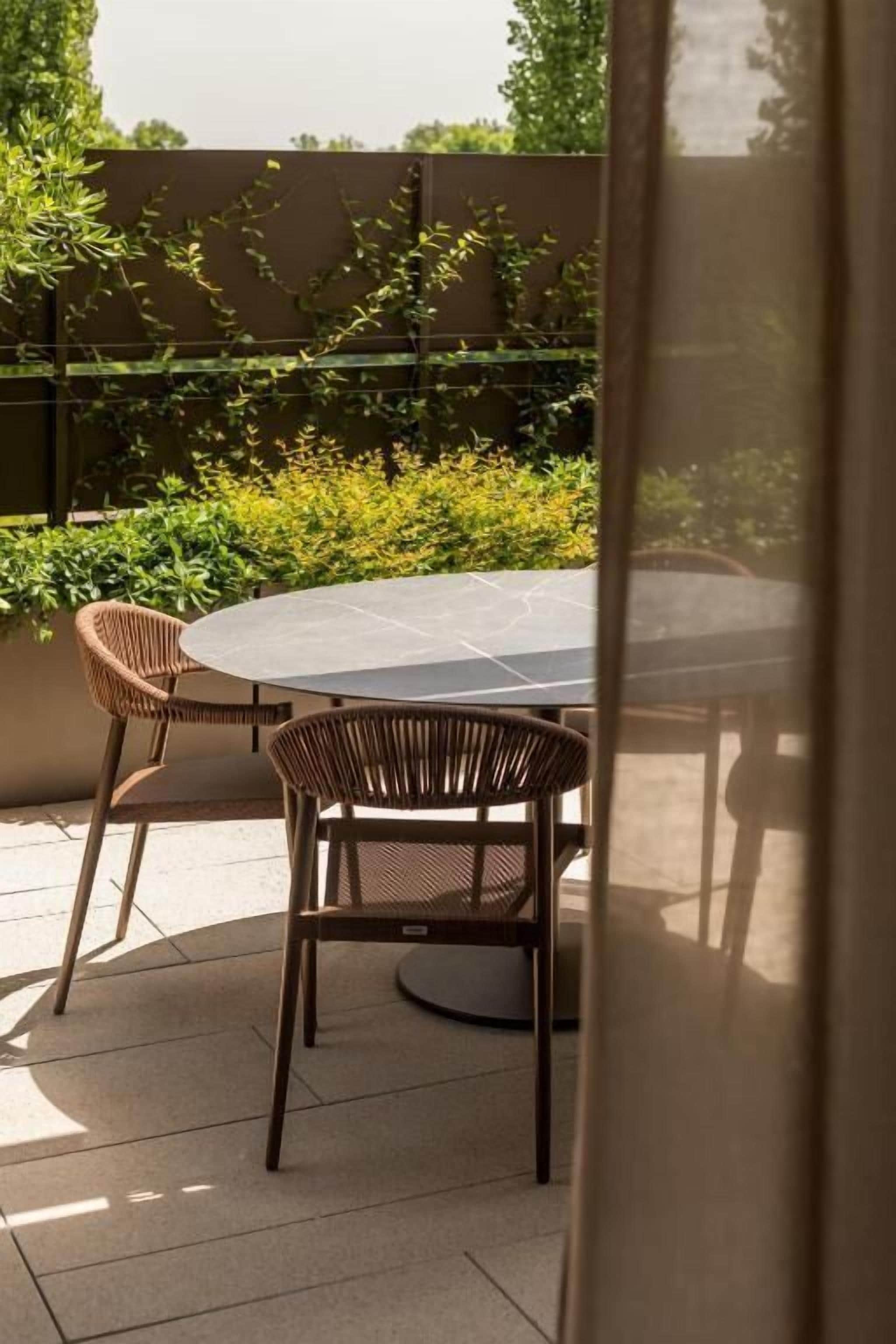 Un patio al aire libre con una mesa redonda y dos sillas de mimbre.
