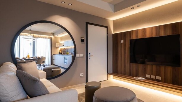 A modern living room with a round mirror, a flat-screen TV, and a sofa. - Stemor srl (Desenzano del Garda)