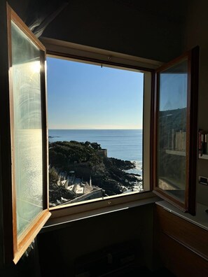 A room with a large window overlooking a rocky coastline and the sea. - Cala Verde House, apartment with beach access, private umbrella, and lounge chairs (Castiglioncello)