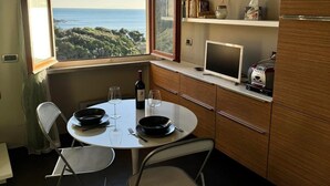 Eine kompakte Küche mit Esstisch, Stühlen, Meerblick, einer Uhr und einem Kühlschrank.