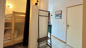 A dormitory room with bunk beds, a metal shelf, a door, and a framed picture on the wall. - Apartment with mountain and slope views (Combloux)