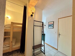 A dormitory room with bunk beds, a metal shelf, a door, and a framed picture on the wall. - Apartment with mountain and slope views (Combloux)