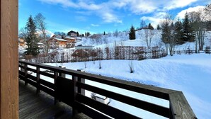 A wooden deck with a view of a snowy landscape, including houses and trees. - Apartment with mountain and slope views (Combloux)