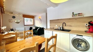 A compact living space with a dining area, kitchen, and a washing machine. - Apartment with mountain and slope views (Combloux)