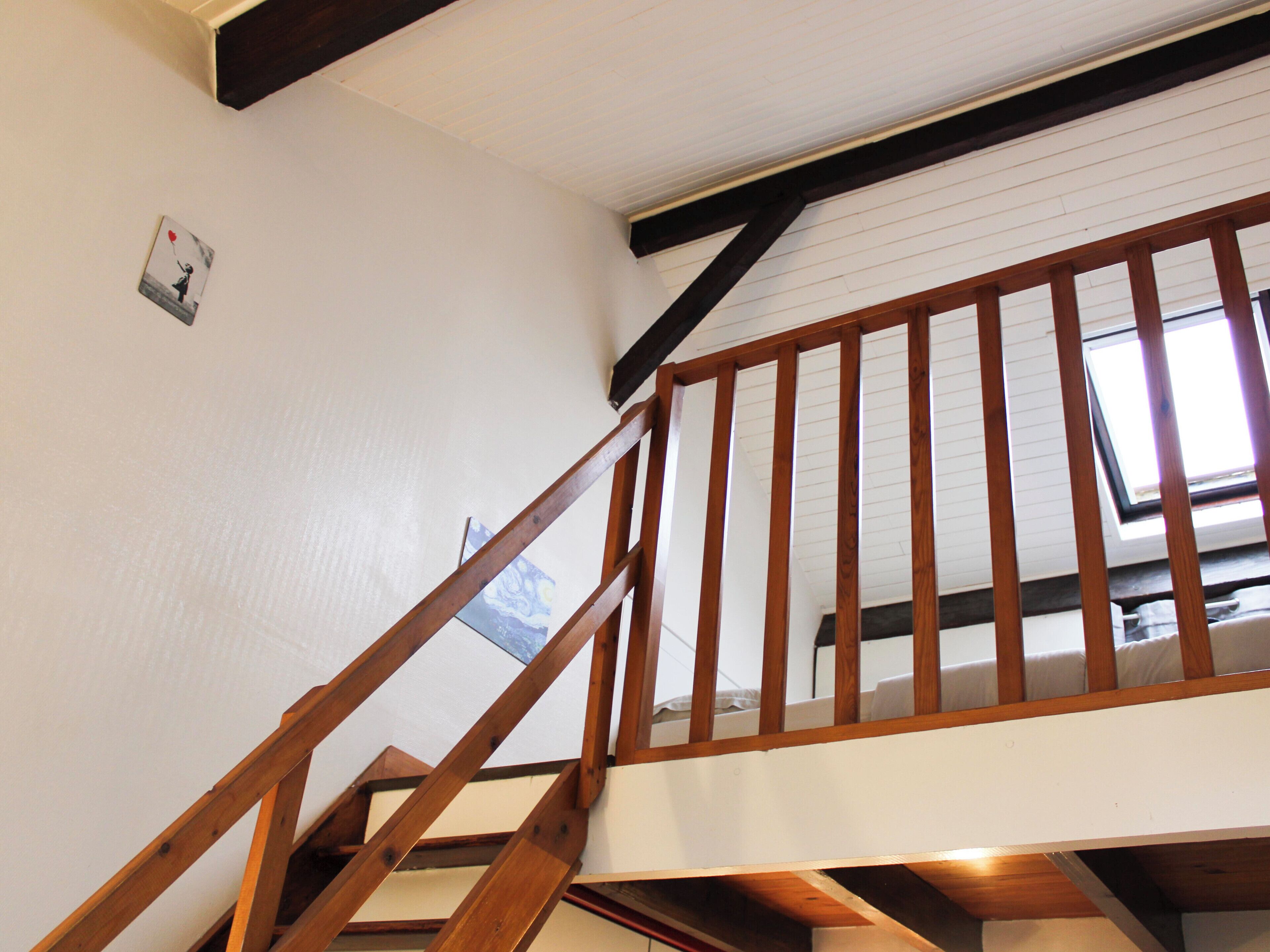 A wooden staircase with a sloped ceiling and a skylight.