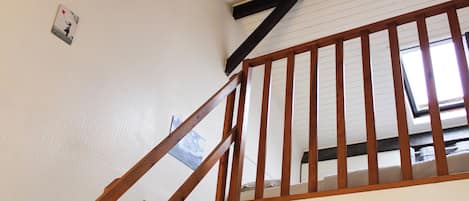 A wooden staircase with a sloped ceiling and a skylight.