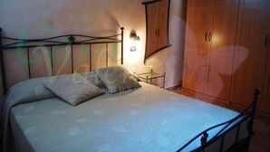 Ein Schlafzimmer mit einem Bett, einem Nachttisch, einer Lampe und einem Holzschrank.
