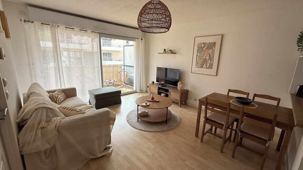 A living room with a sofa, coffee table, TV, and dining table.