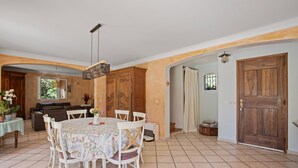 Un espace repas comprenant une table ronde, des chaises, un luminaire suspendu et des meubles de rangement en bois.