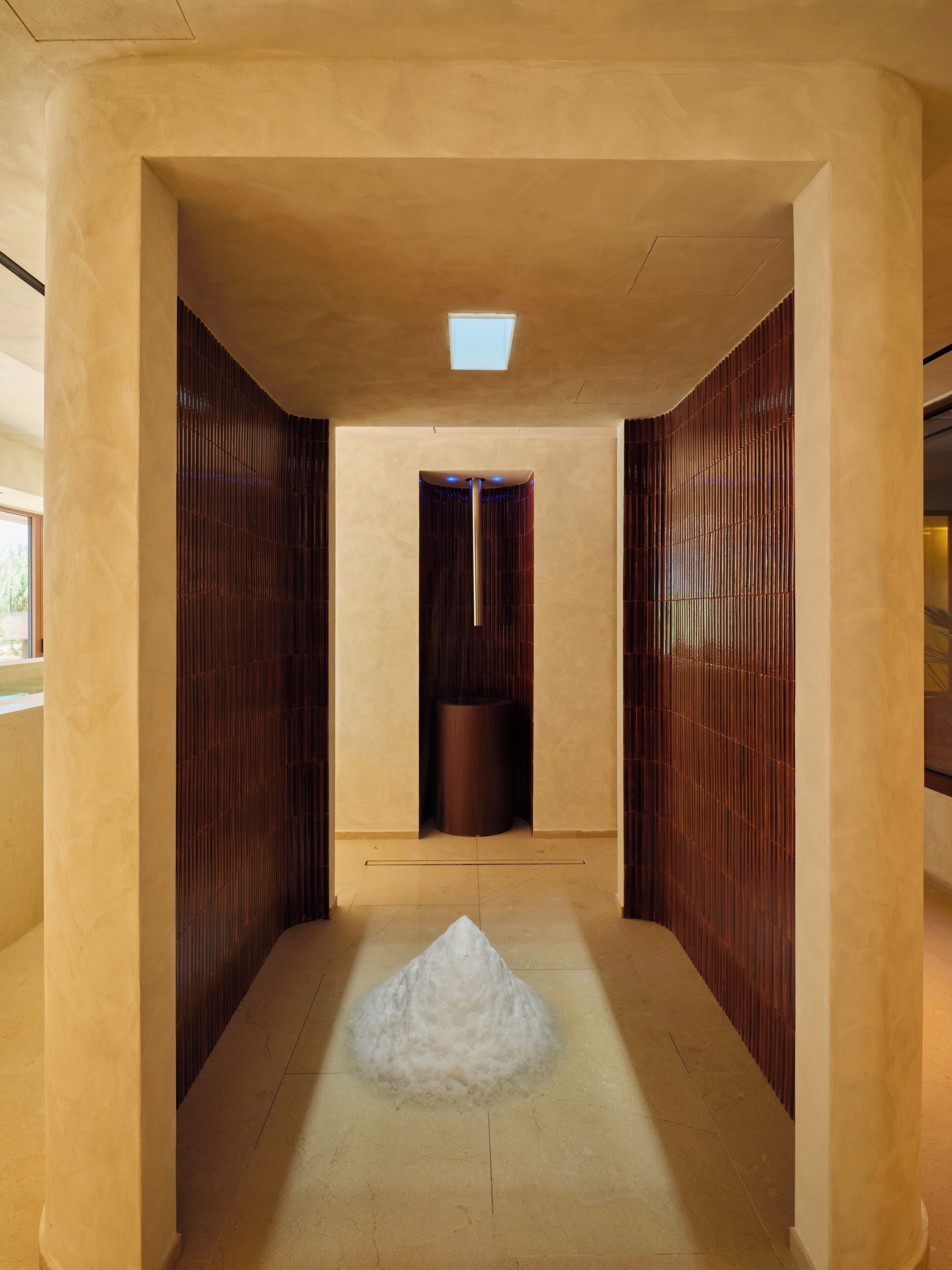 A hallway with a central column, a patterned wall, and a light fixture.