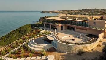 Una moderna proprietà costiera con una grande piscina esterna, un patio e vista sul mare.