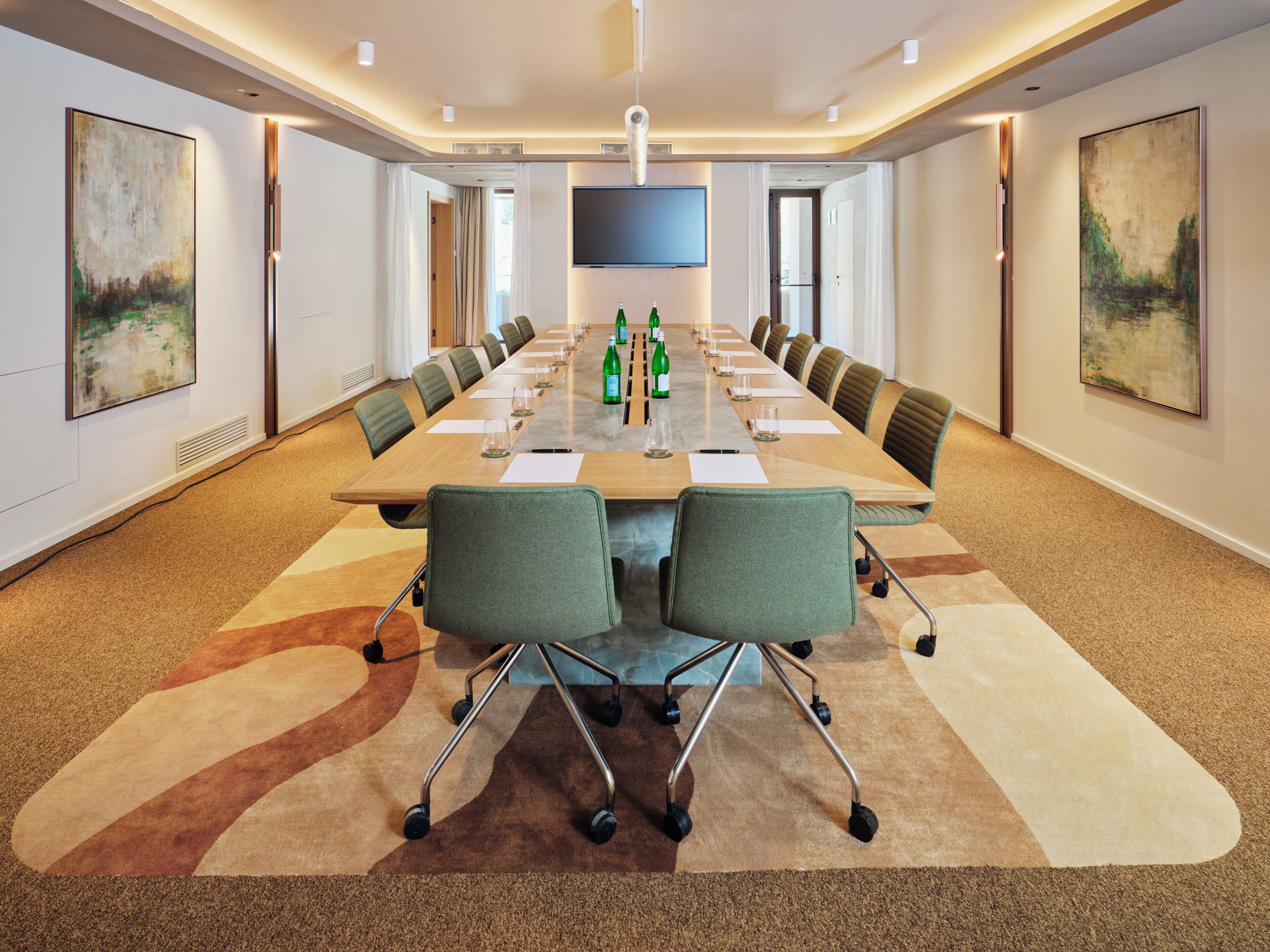 A conference room with a long table, chairs, and a flat-screen TV.