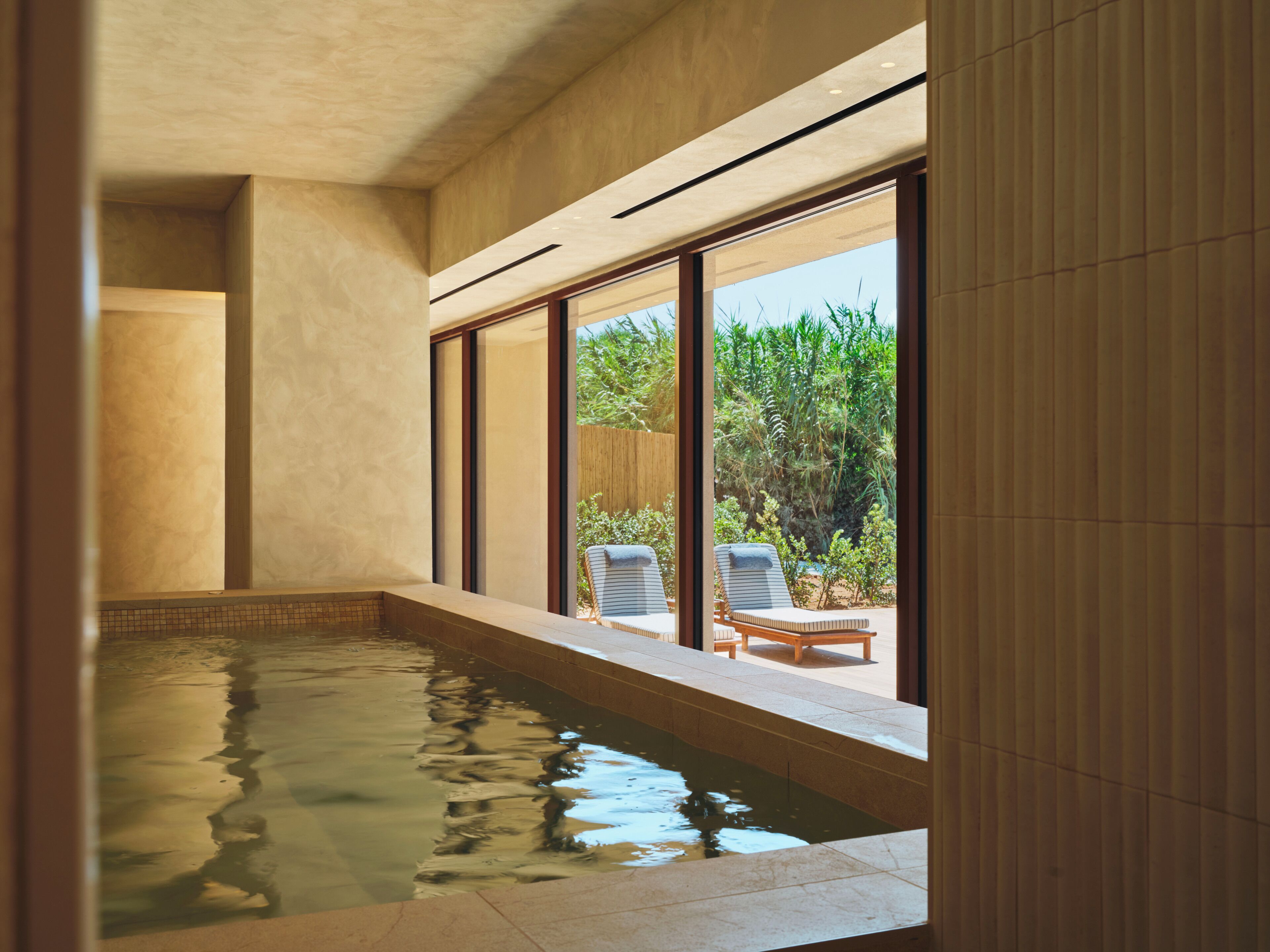 Area benessere con piscina, ampie finestre e poltrona relax.