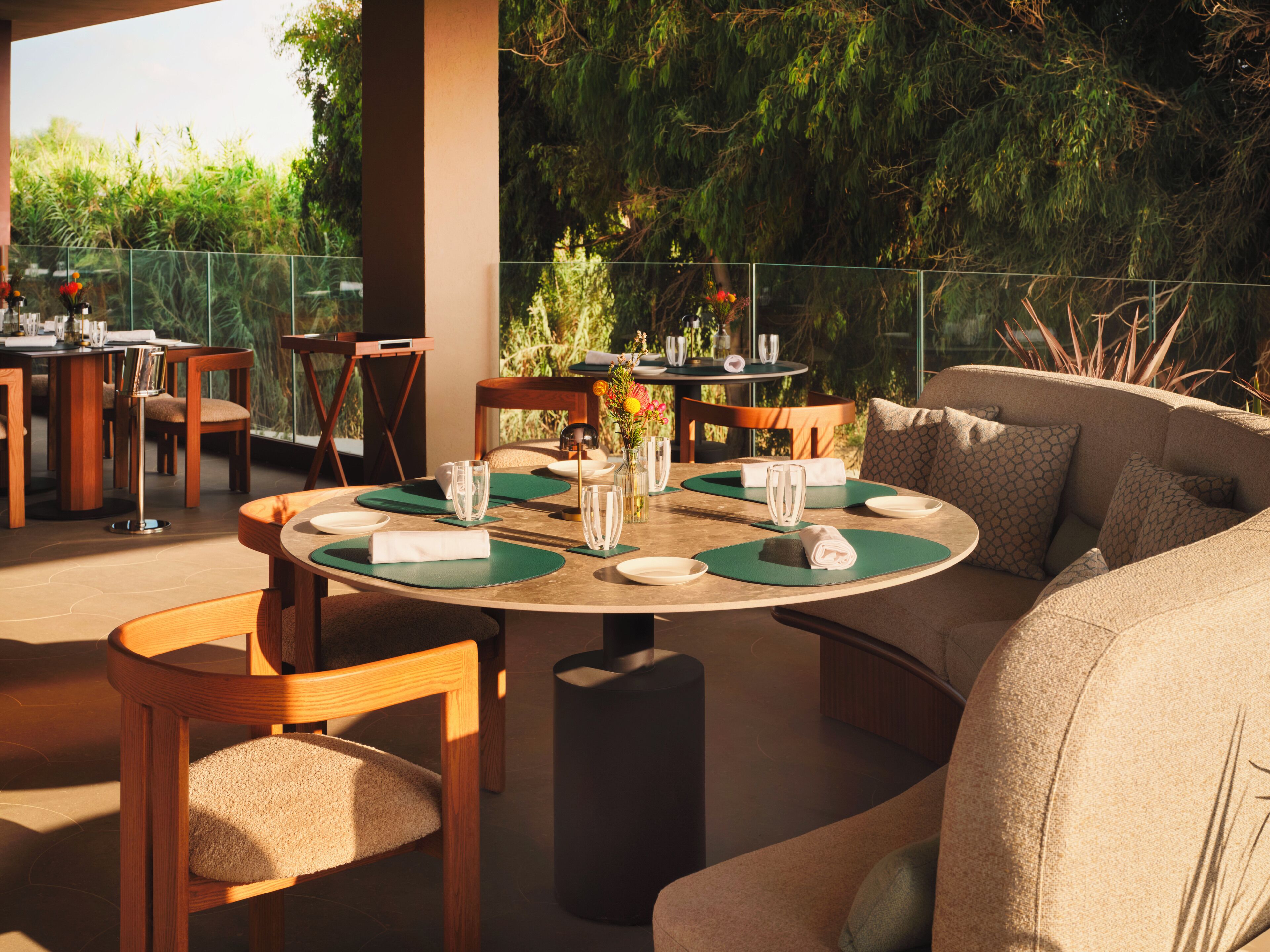 Un espace extérieur aménagé pour les repas, avec des tables rondes, des chaises et un canapé.