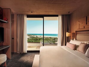 A hotel room with a large bed, a TV, a desk, and a view of the beach. -  Icona's Costa Ragusa Resort (Scoglitti)