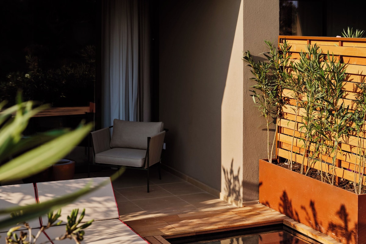 A pool area with a wooden deck, a lounge chair, and a planter with plants.