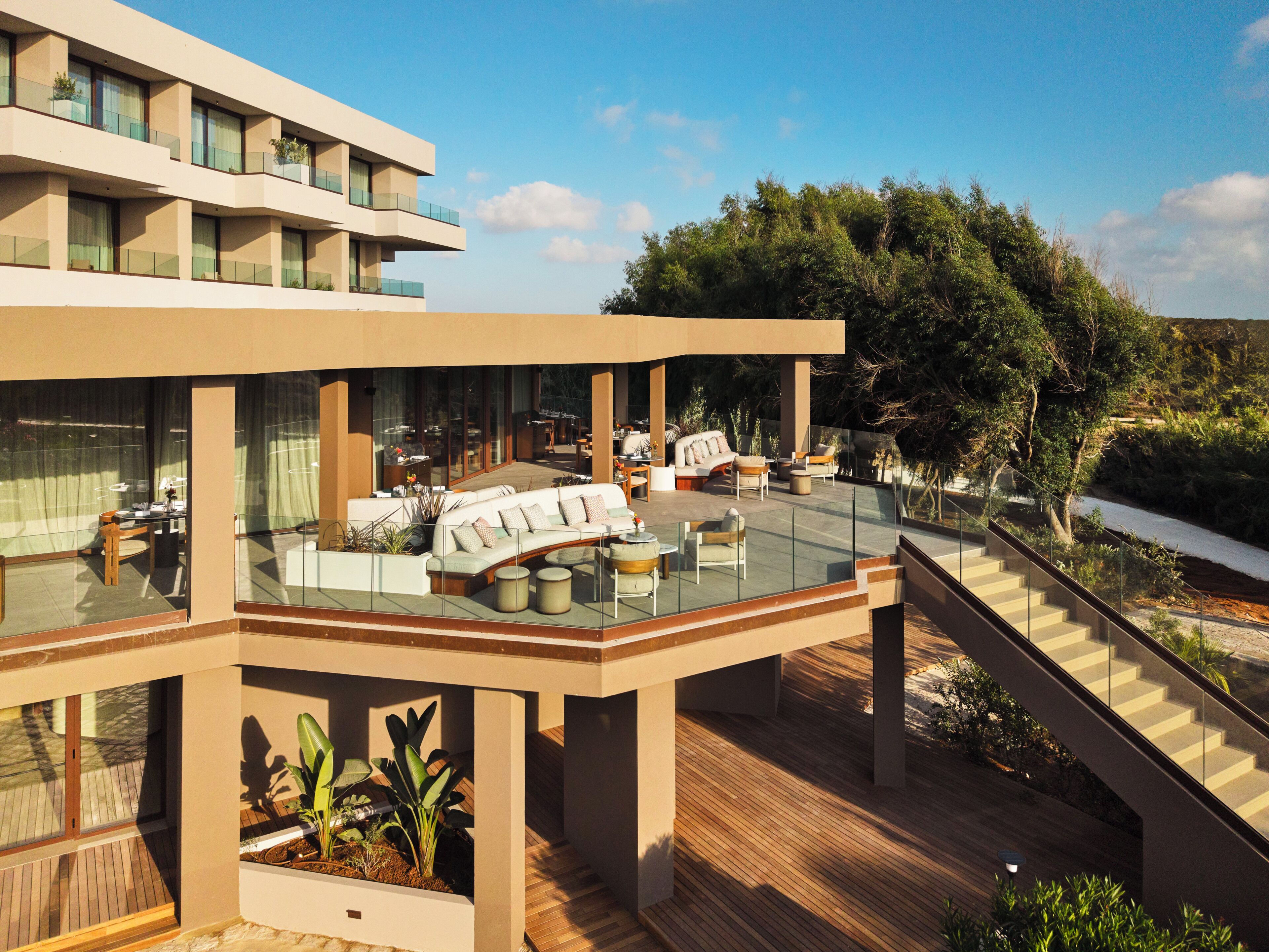 Un bâtiment moderne doté d’une terrasse sur le toit, comprenant un espace de détente extérieur et un escalier.