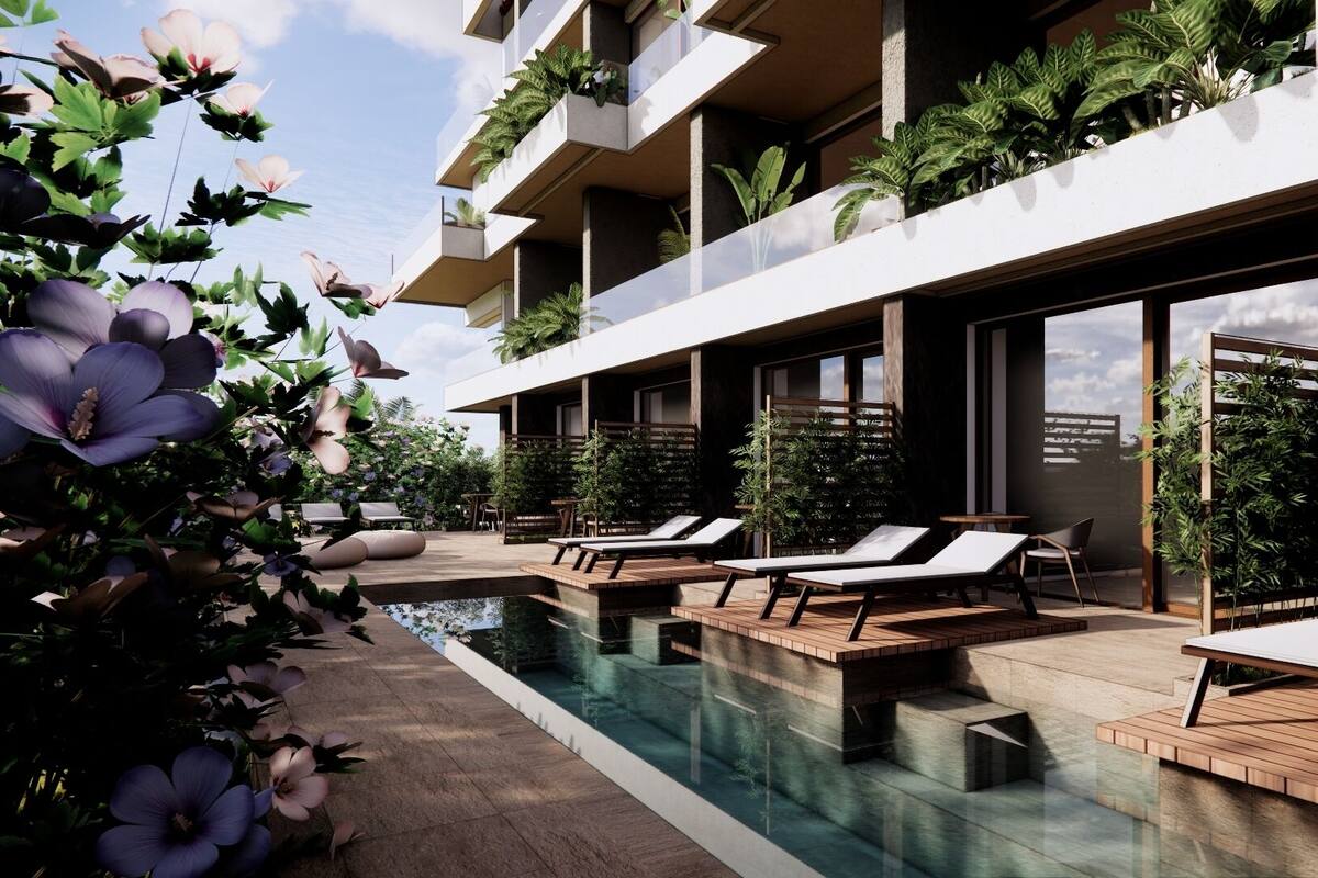 A modern hotel with a pool, lounge chairs, and greenery.