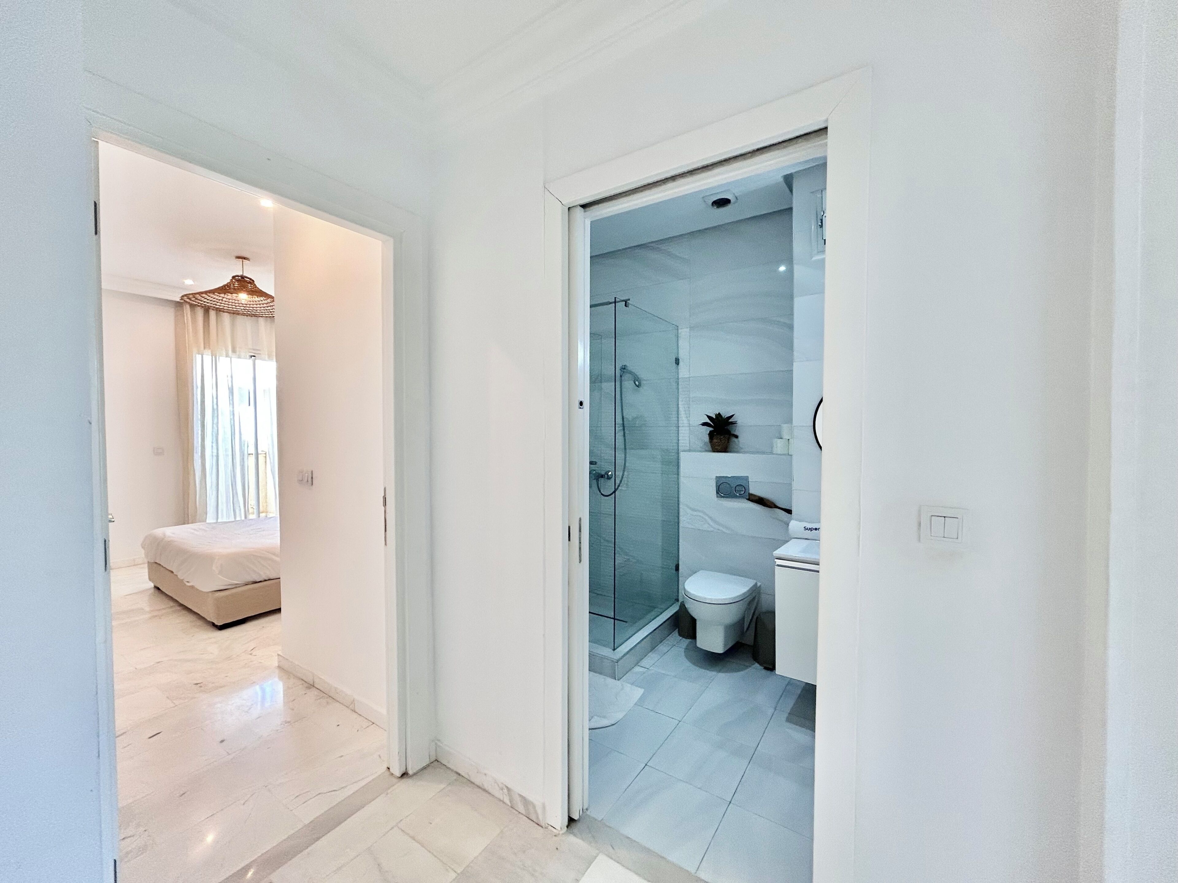 A modern bathroom with a glass shower, a toilet, and a sink.