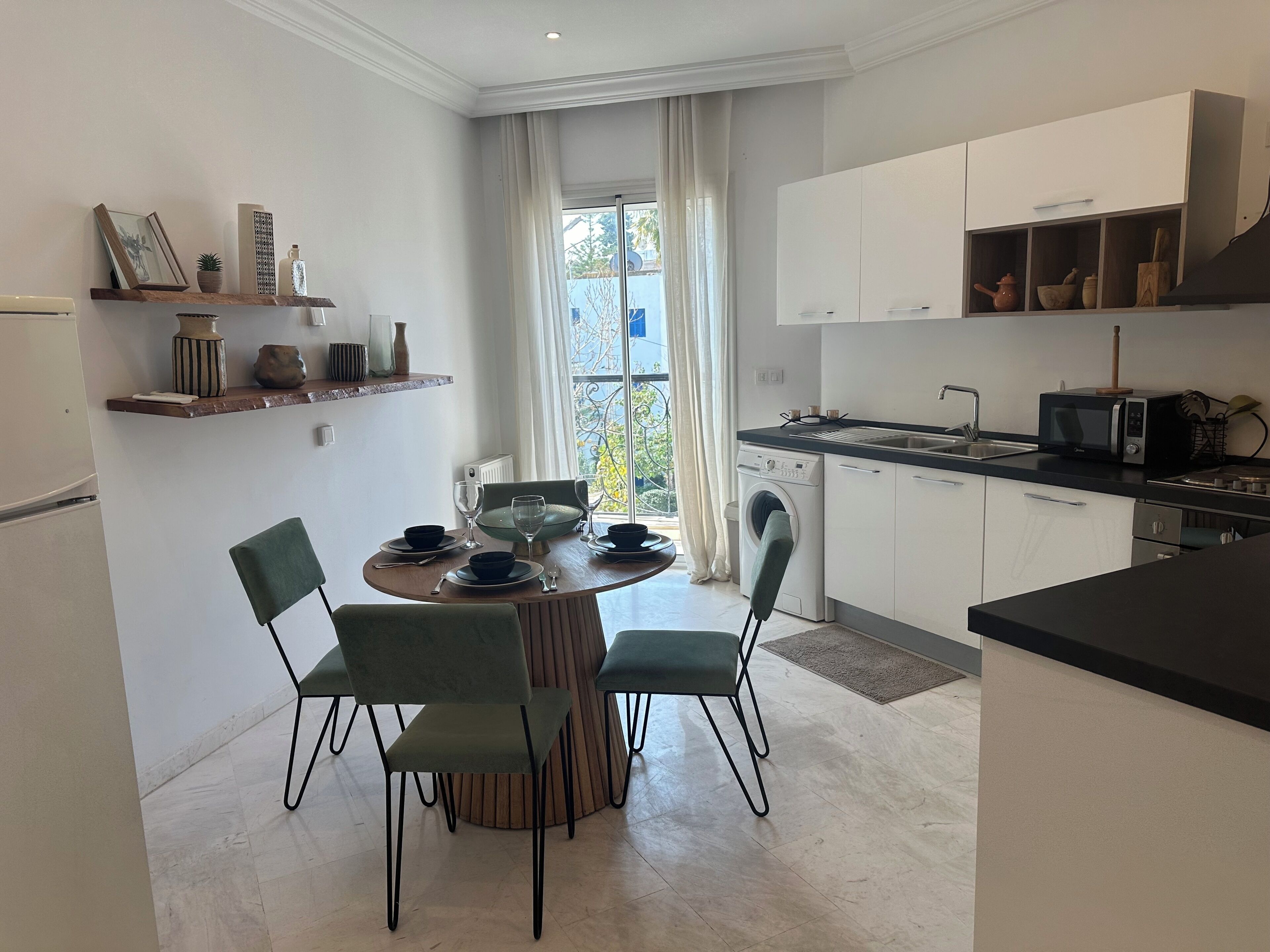 Una cocina moderna con comedor, que incluye una mesa redonda, sillas, horno empotrado y microondas.