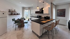 Una cocina moderna con una isla central, electrodomésticos integrados e iluminación colgante.