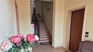 Un couloir avec un escalier, une porte et une chaise.