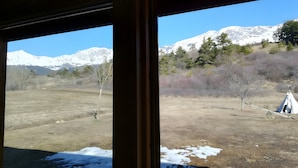 A window view of a mountainous landscape with a tent and sparse vegetation. - Le chalet neige – Chorges Hautes-Alpes (Chorges)