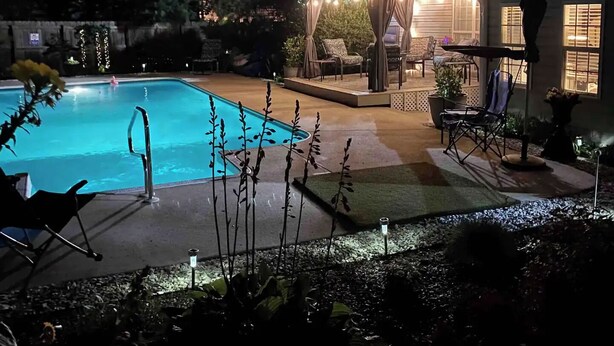 Ein Schwimmbad mit überdachter Sitzgruppe und Liegestühlen.