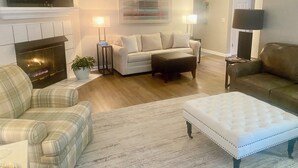 Ein Wohnzimmer mit Kamin, einer Couch, einem Zweisitzer und einem Couchtisch.