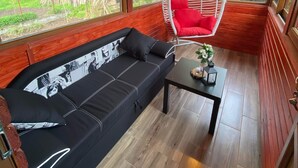 A cozy room with a black sofa, a hanging chair, and a small table. - Enchanting 2-bedroom house with AC and Barbecue in charming Mălaia (Mălaia)