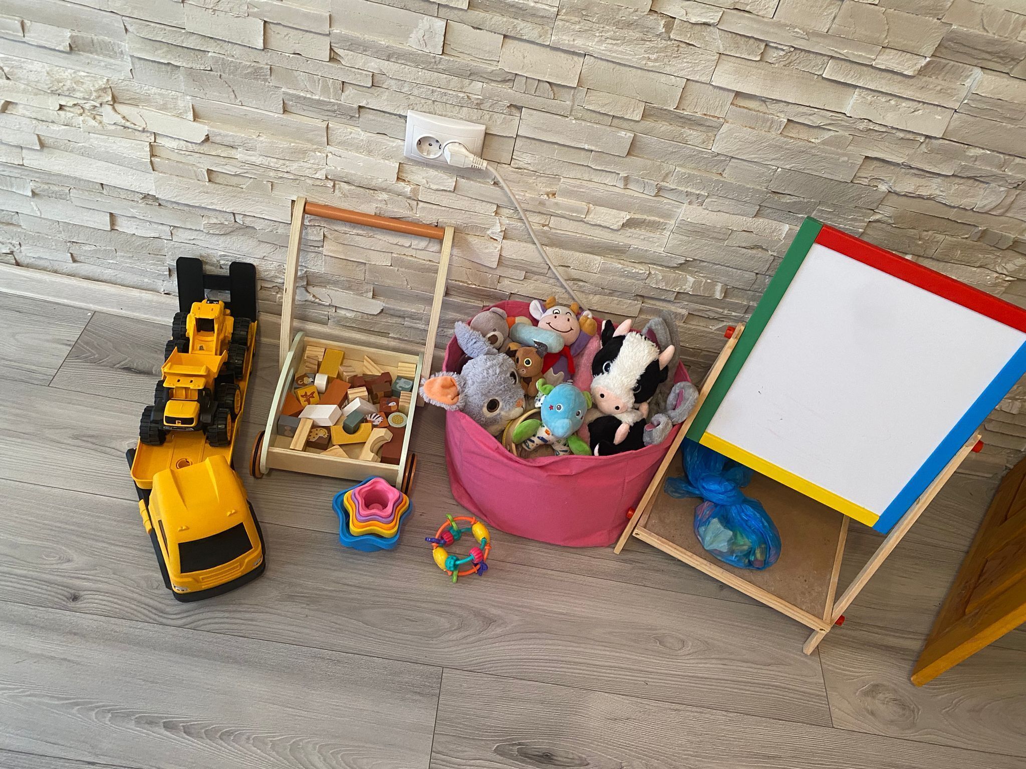 A child's play area with toys, a toy truck, a wooden box, and a whiteboard.