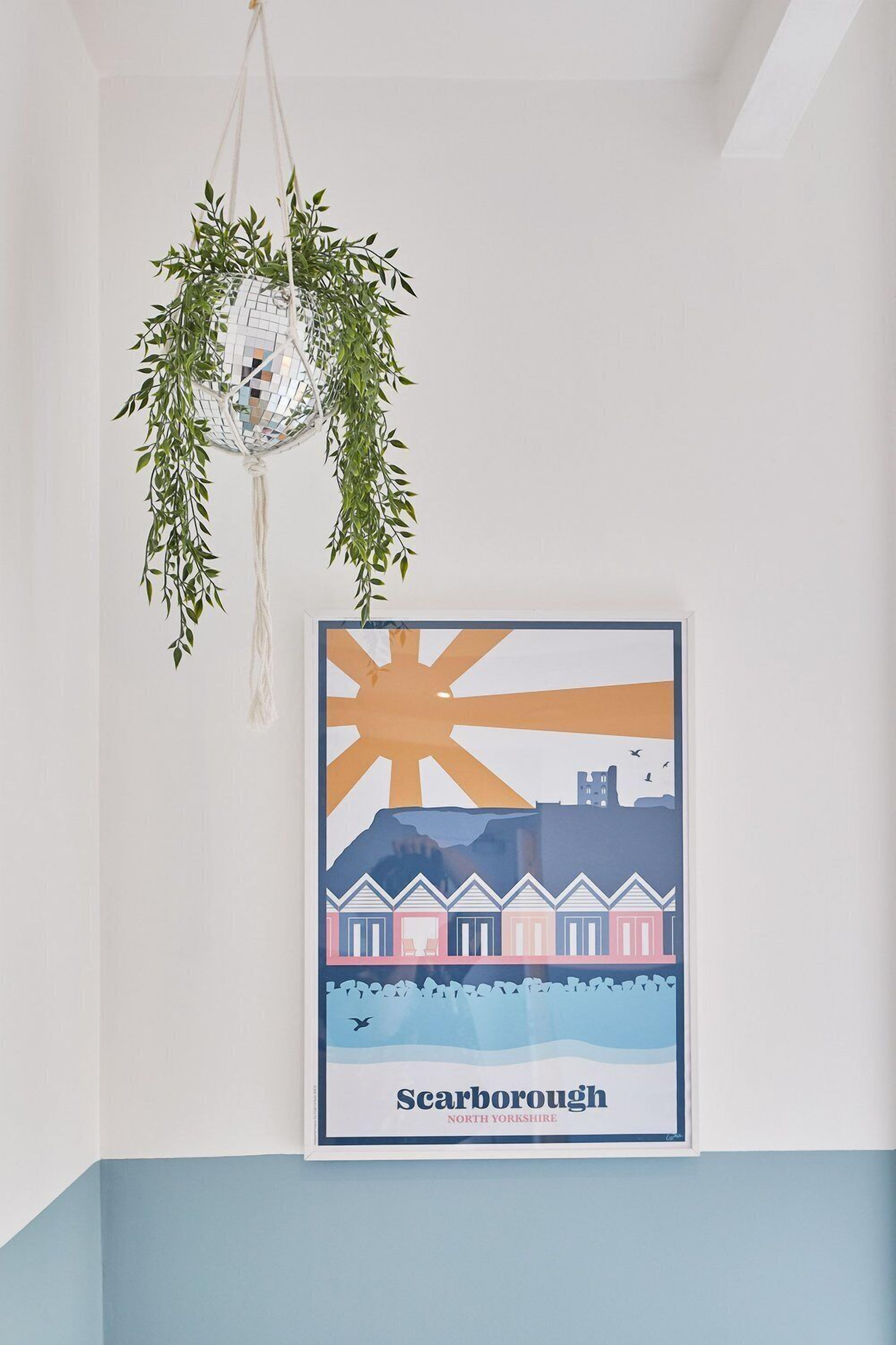 A framed poster of Scarfborough, North Yorkshire, featuring a sun and houses.