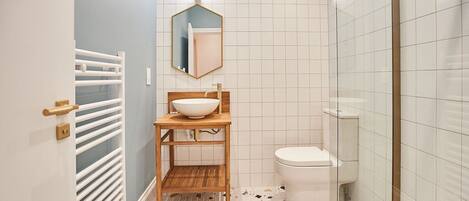 Une petite salle de bain avec un lavabo blanc, un miroir et des toilettes.