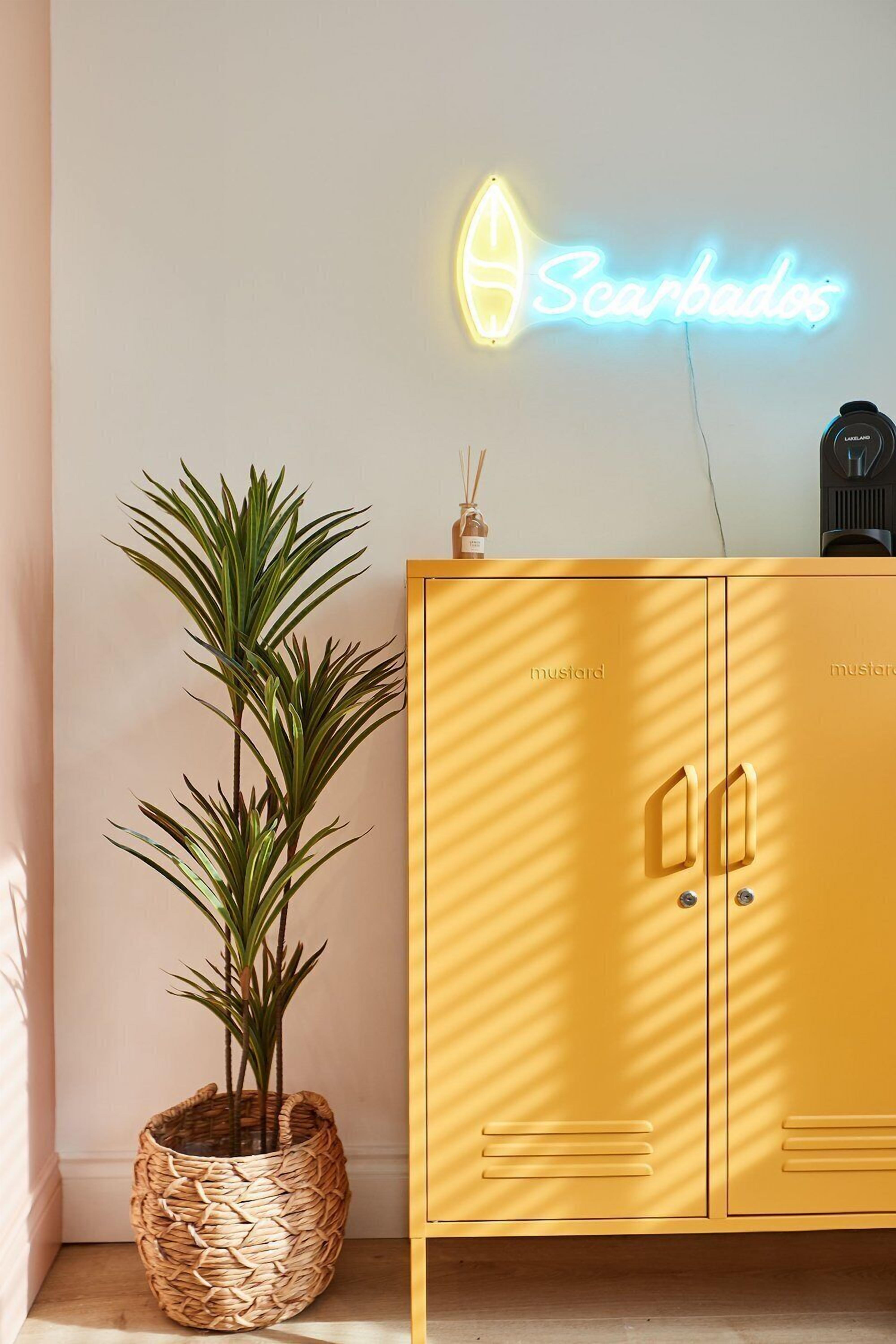 A yellow cabinet with the word "mustard" on it, a neon sign that reads "Scarados", and a potted plant.