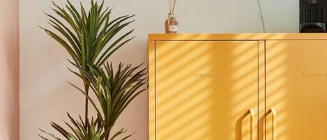 A yellow cabinet with the word "mustard" on it, a neon sign that reads "Scarados", and a potted plant.