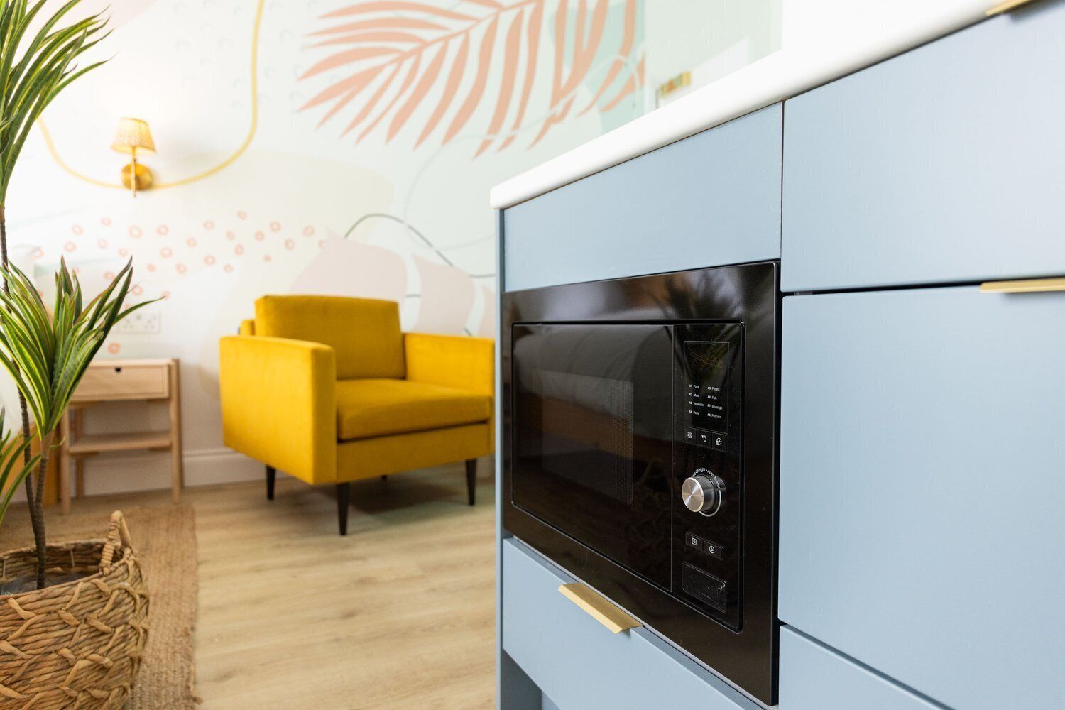 Una cocina moderna con microondas integrado, una silla amarilla y una pequeña mesa.