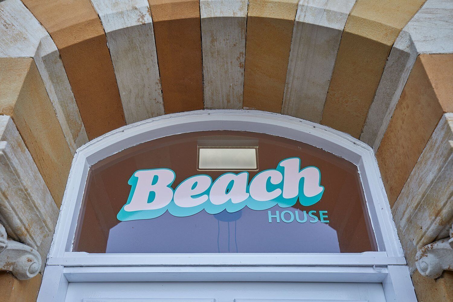 A sign for 'Beach House' with a classic arched entrance and a decorative stone facade.