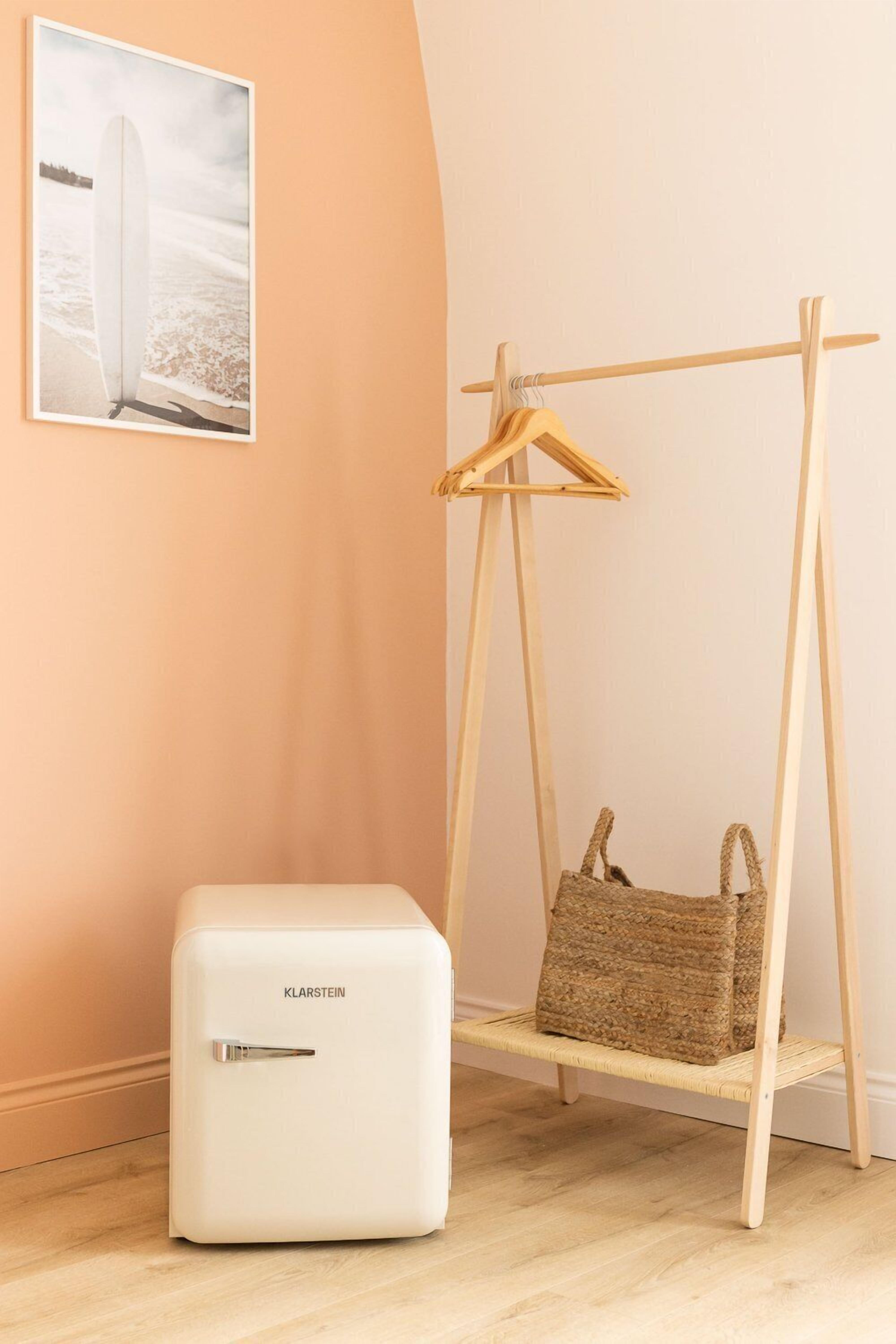 A white refrigerator, a wooden swing chair with a woven bag, and a framed picture on the wall.