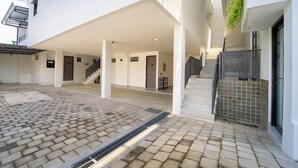 A modern building with a covered outdoor area, a staircase, and a tiled floor. - Artric Profesional Living by ARBA (Semarang)