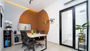 A modern office space with a conference table, chairs, a water dispenser, and potted plants. - Artric Profesional Living by ARBA (Semarang)