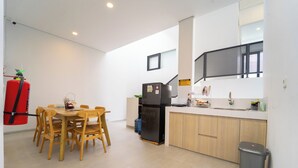 A modern kitchen with wooden chairs around a table, a black refrigerator, and a red fire extinguisher. - Artric Profesional Living by ARBA (Semarang)