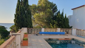 Zona de piscina con una silla de descanso, una piscina pequeña y vistas al mar.