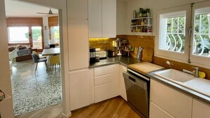 Una cocina moderna con armarios blancos, horno empotrado y un ventanal con vistas al verdor.