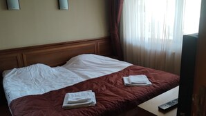 A hotel room with a bed, a TV, and a window with curtains. - Hotel Sofia (Bansko)