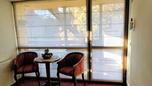 A room with two chairs, a small table, and a large window. - Hotel Sofia (Bansko)