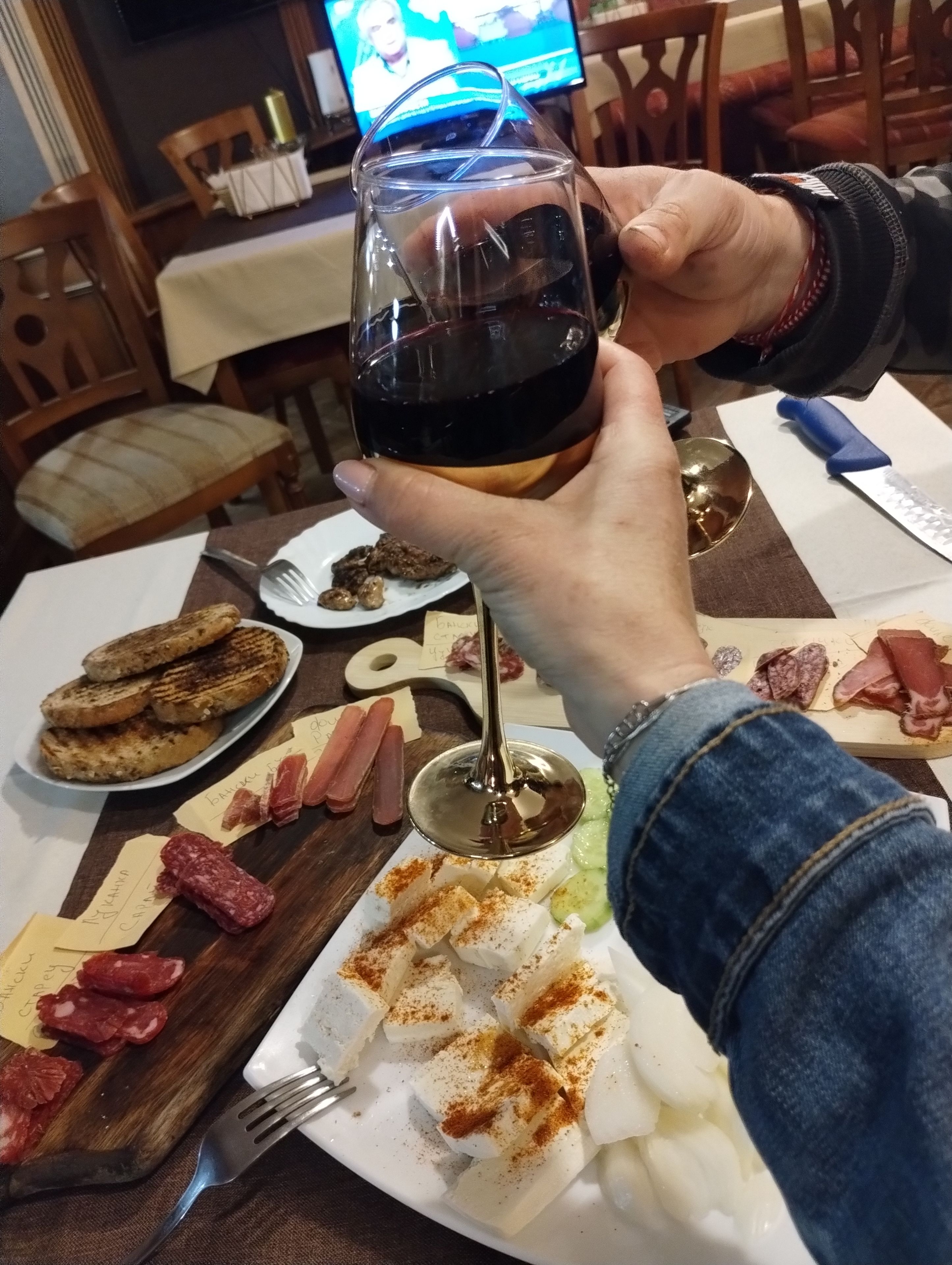 A dining table with a plate of food, a glass of red wine, and a knife.