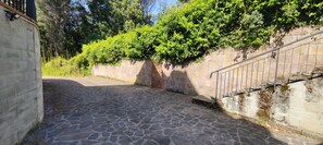 A cobblestone pathway leading to a stone wall with a metal railing. - [Karamazov House] Chianti Florence (Romola)