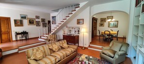 Un salon avec un escalier, un coin repas et une bibliothèque.