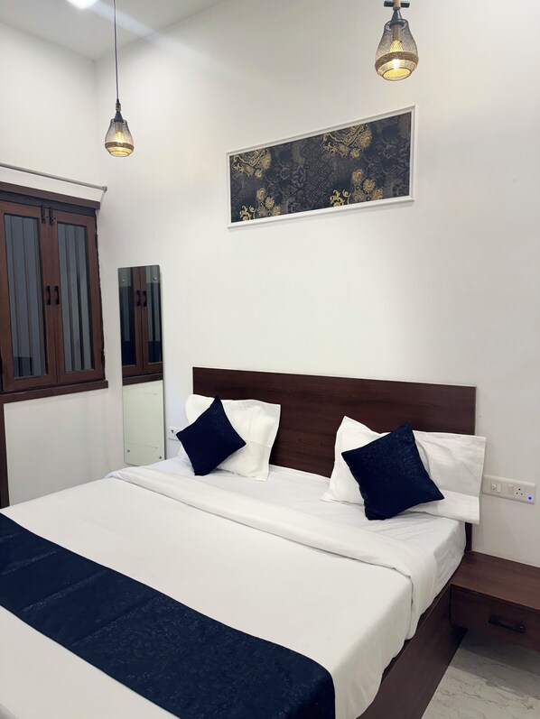Une chambre à coucher bien aménagée, avec un grand lit, deux tables de chevet, une commode, une œuvre d’art accrochée au mur et une fenêtre donnant sur un beau paysage.